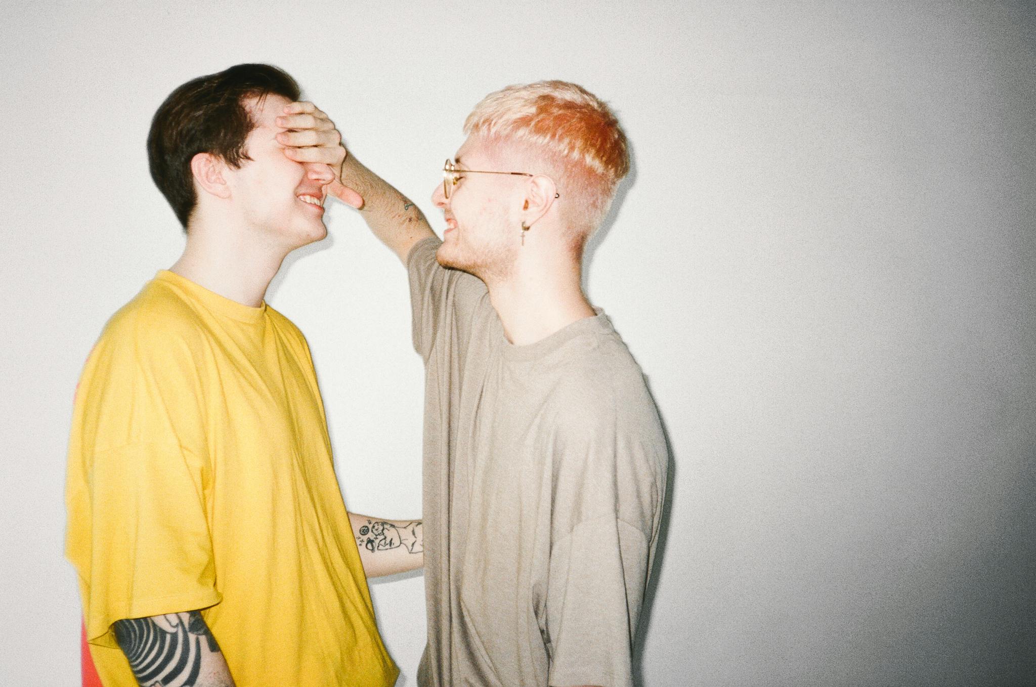 Two men sharing a playful, intimate moment indoors. LGBTQ+ love and happiness.